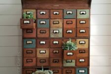 23 a vintage stained and painted card cabinet styled with greenery, with a sign and books is a cool and chic idea