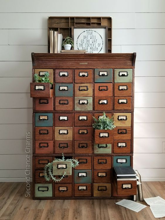 A vintage stained and painted card cabinet styled with greenery, with a sign and books is a cool and chic idea