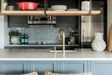 31 a light grey and graphite grey kitchen with a grey tile backsplash, suspended shelves, woven stools and brass and gold fixtures