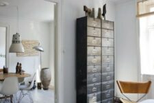 32 a light-filled Scandinavian space with a dark card cabinet that is used instead of a usual dresser and a leather chair