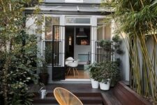 35 a small minimalist paved patio with a dark stained deck and a tiled floor, with growing bamboo and plants and chic woven chairs and a table