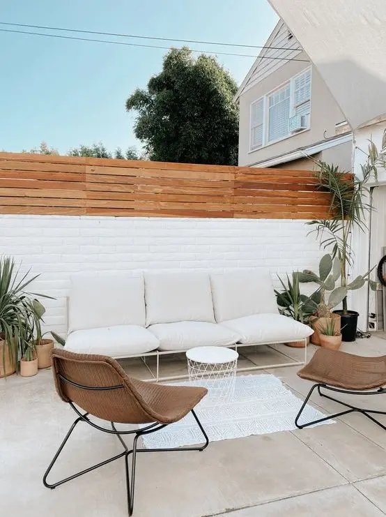 a stylish contemporary backyard with some potted cacti and succulents, with a neutral sofa, wicker chairs and a small side table