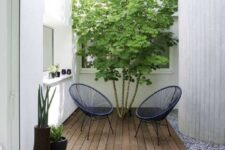 56 a small modern backyard with a wooden deck, navy woven chairs, a living tree and some potted plants is cool and chic