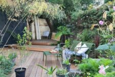 58 a lovely and welcoming garden with a raised wooden deck of several layers, greenery and blooms in raised garden beds