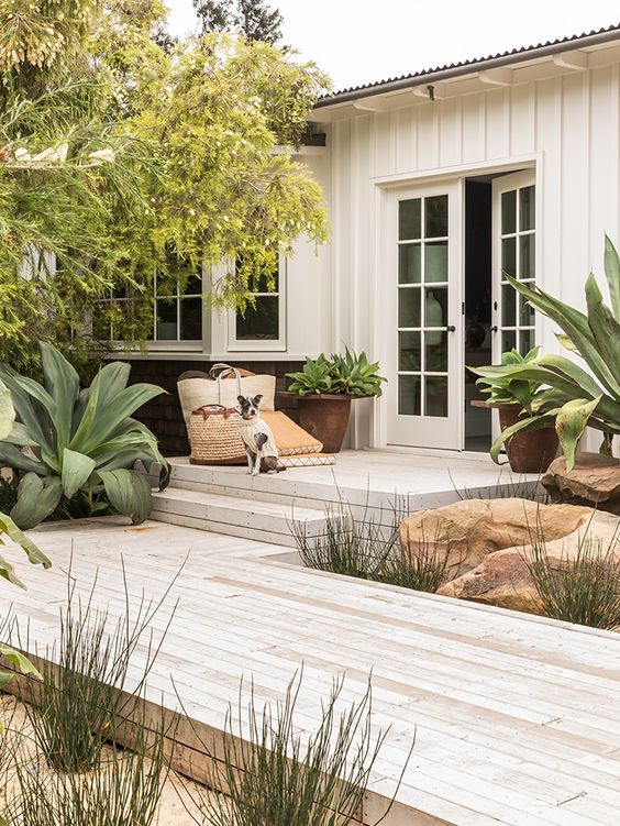 a lovely outdoor space with a whitewashed wooden deck, potted plants and some rocks is awesome