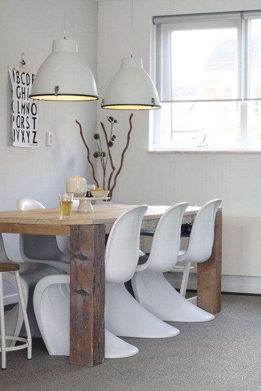 a Scandinavian dining space with a stained table, white Panton chairs, white pendant lamps and some simple decor