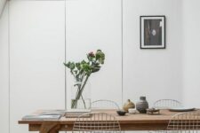 a Scandinavian dining space with skylights, a stained table, Eames wire chairs, some decor and an artwork