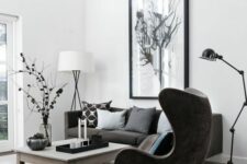 a Scandinavian living room with a graphite grey sofa and pillows, a black Egg chair, a low coffee table, an oversized artwork and a floor lamp