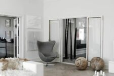 a Scandinavian living room with some large balls for decor, a white sofa with faux fur, a black coffee table and a grey Egg chair