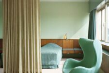 a beautiful space done in tan, light green and aqua, with a bed and floating nightstands, an aqua Egg chair and a sofa