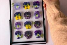 a black metal frame with bright pansies inside is an amazing artwork to place on the table or on the wall