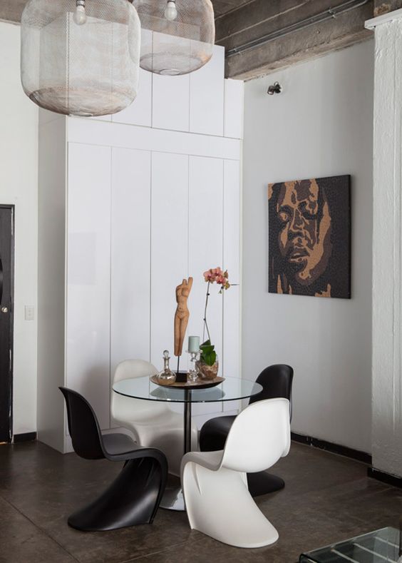 a bold dining room with a glass dining table, black and white Panton chairs, an artwork and some lovely decor is a cool space