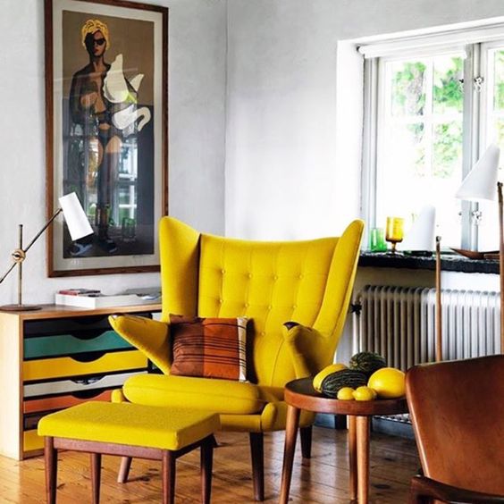 a bold space with a colorful storage unit, a yellow Papa Bear chair and a footrest, a side table and a lamp