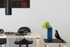 a catchy dining room with a stained table and black Eames wire chairs, a trolley with some decor and black pendant lamps