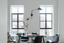 a catchy dining space with a glass dining table, mismatching black chairs including Panton and Tulip ones and a black sconce