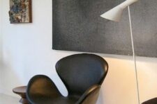 a contrasting nook with a graphite artwork, a black Swan chair, a white floor lamp, a sofa and pillows and a side table