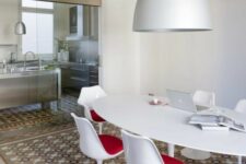 a cool dining and working space with a bold floor, an oval table, red Tulip chairs and a pendant lamp