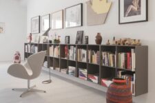 a cool reading space with a grey floating bookcase, a gallery wall, a white Swan chair, a bold side table is cool