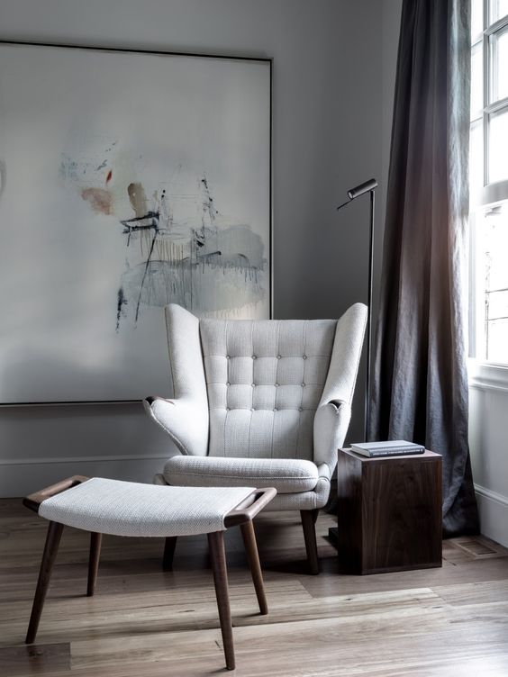 a delicate nook with an oversized artwork, a white Papa Bear chair, a footrest, a side table and a black floor lamp