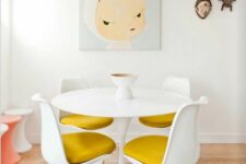 a fun dining space with a round table, mustard Tulip chairs, a fun artwork and Asian decor on the wall, colorful stools