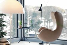 a gorgeous glazed space with a tan leather Egg chair, a side table and a black floor lamp plus some amazing views