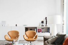 a lilvely living room with a taupe sofa and bold pillows, amber leather Swan chairs, a coffee table and a white storage unit