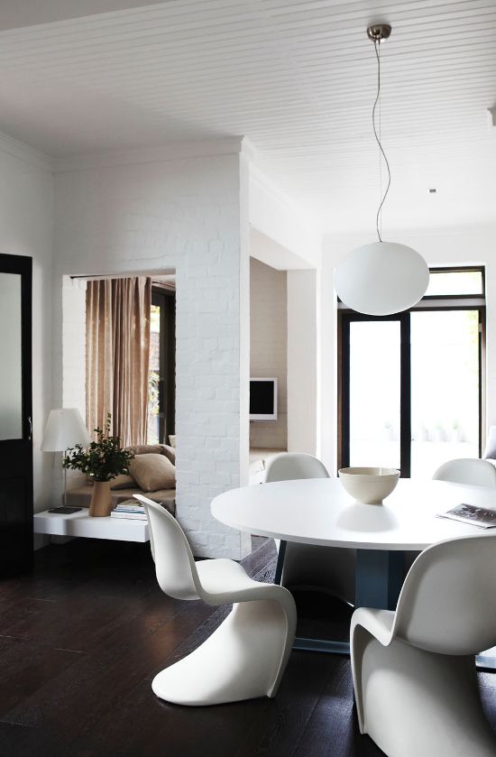 a modern neutral dining space with a round table, white Pantone chairs and a pendant lamp is cool and edgy