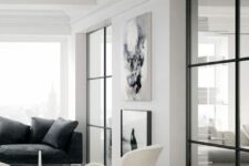 a neutral Scandinavian living room with a black sofa and pillows, creamy Swan chairs, black and white artwork