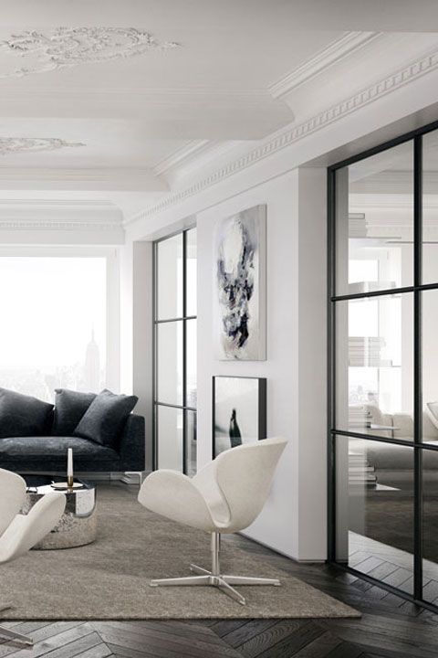 a neutral Scandinavian living room with a black sofa and pillows, creamy Swan chairs, black and white artwork