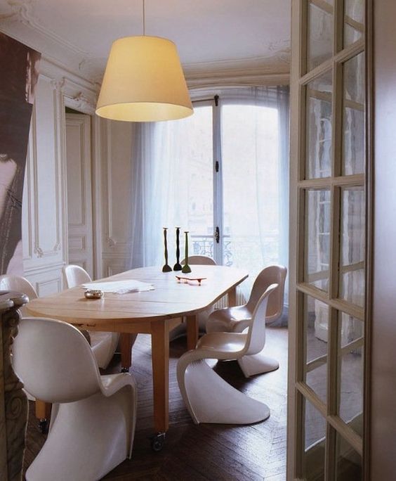 a refined modern dining room with a stained table, white Panton chairs, some decor and stucco on the walls is cool