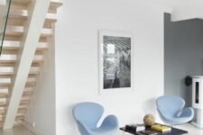 a small and stylish space with a black coffee table, light blue Swan chairs, a black and white artwork is a cool nook