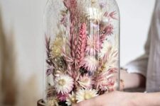 a small flower dome filled with pink and neutral dried blooms and grasses is a lovely spring or summer decoration
