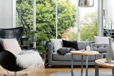 a stylish Scandinavian living room with a black Egg chair and some pillows, a grey sofa, a rug and some coffee tables, a floor lamp