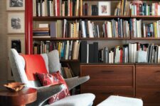 a stylish reading space with a large bookcase, a neutral Papa Bear chair with a footrest, a side table and art