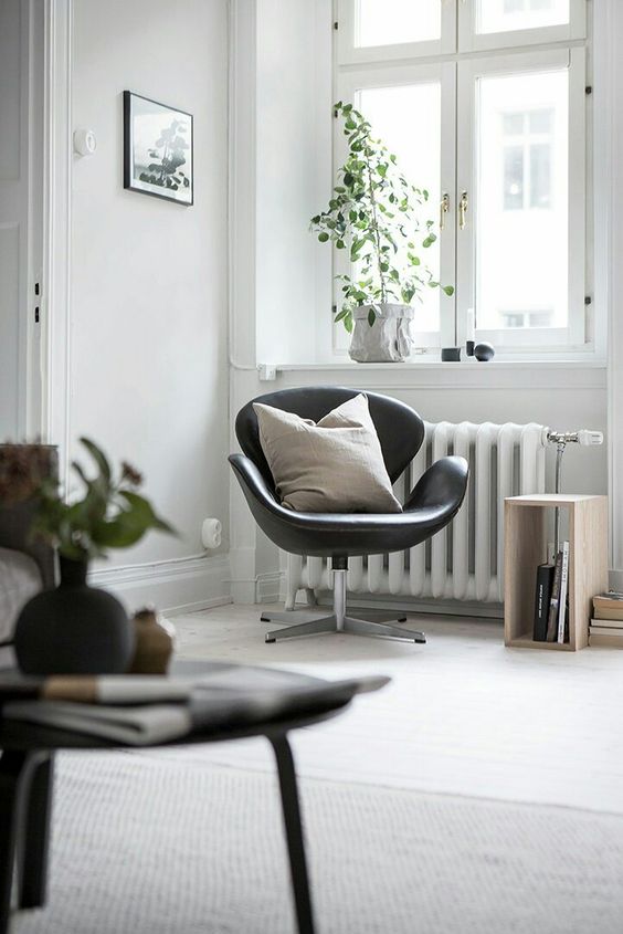 an airy Scandinavian space with a black leather Swan, potted plants, a crate as a side table and some artwork