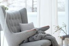 an airy Scandinavian space with a grey Papa Bear chair with a pillow and a blanket, a white floor lamp and a candle