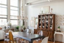 an eclectic dining room with a stained storage unit, a black dining table, mismatching chairs, a chandelier and lots of various decor