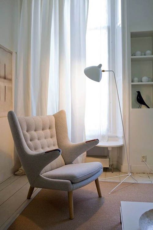 an ethereal Scandinavian space in neutrals with a neutral Papa Bear chair, a floor lamp, some storage units and a neutral rug