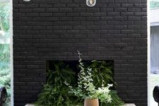 02 a beautiful and refined black brick fireplace filled with greenery and with a gold chandelier over it