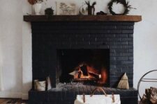 03 a black brick fireplace with a wooden mantel with various plants and some accessories plus a firewood stand next to it