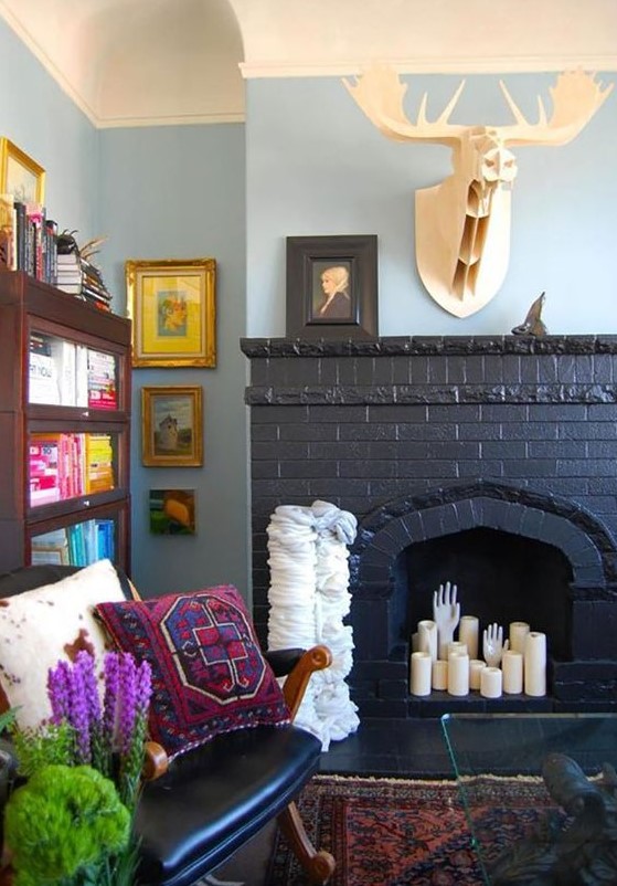 a black brick fireplace with pillar candles and hands, with a faux deer head over it is very cool and bold