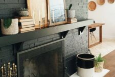 05 a black brick fireplace with white tiles in front of it, a black mantel with books and artworks for stylish monochromatic decor