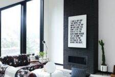 08 a laconic black brick fireplace with a graphic artwork to finish off a monochromatic look and a floral sofa to spruce up the space