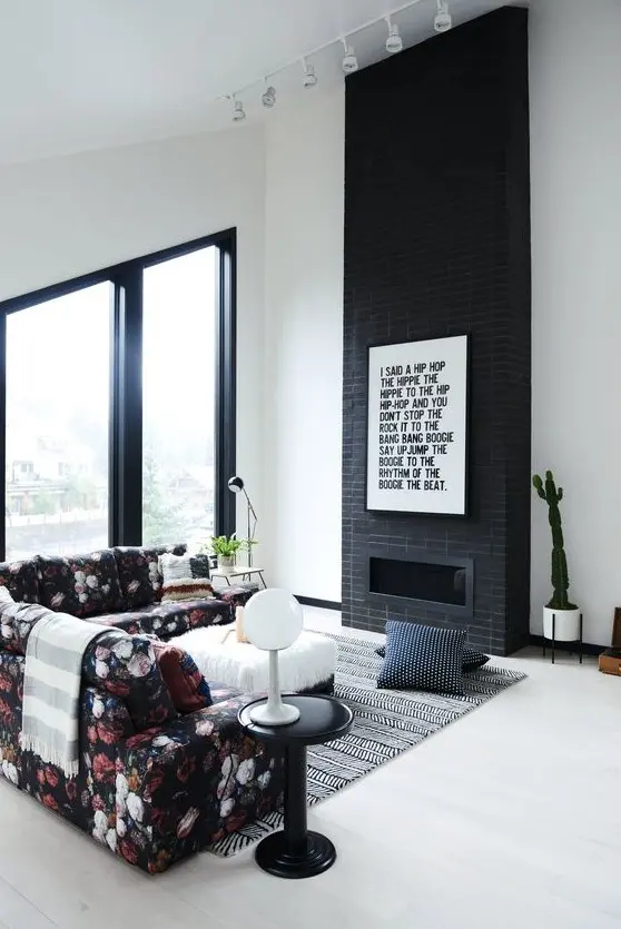 a laconic black brick fireplace with a graphic artwork to finish off a monochromatic look and a floral sofa to spruce up the space