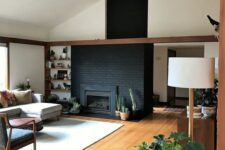 09 a mid-century modern living room with a black brick fireplace, built-in shelves, a neutral sofa, chairs and potted plants
