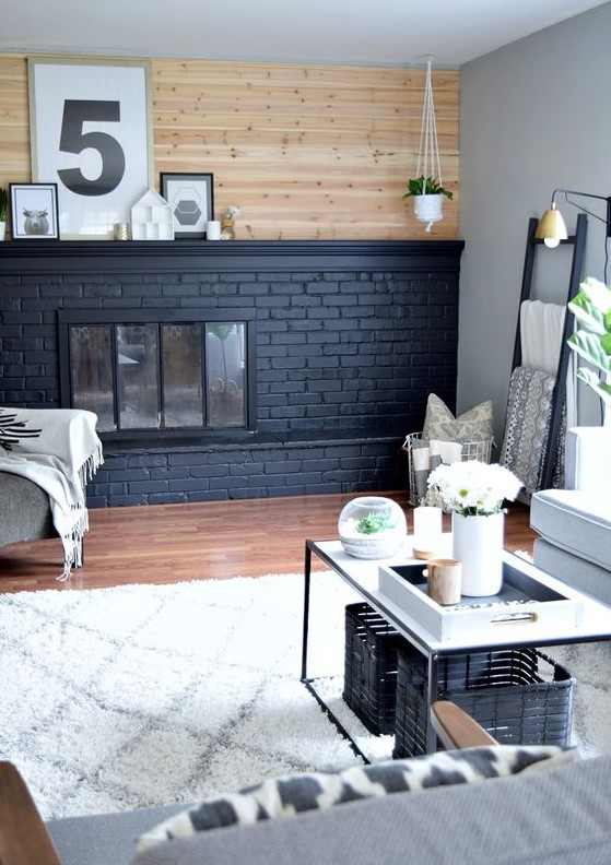 a modern neutral farmhouse living room with a black brick fireplace that contrasts it and a wooden wall over it