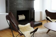 15 an elegant mid-century modern living room with a black painted brick fireplace, leather butterfly chairs, a low coffee table and animal skins