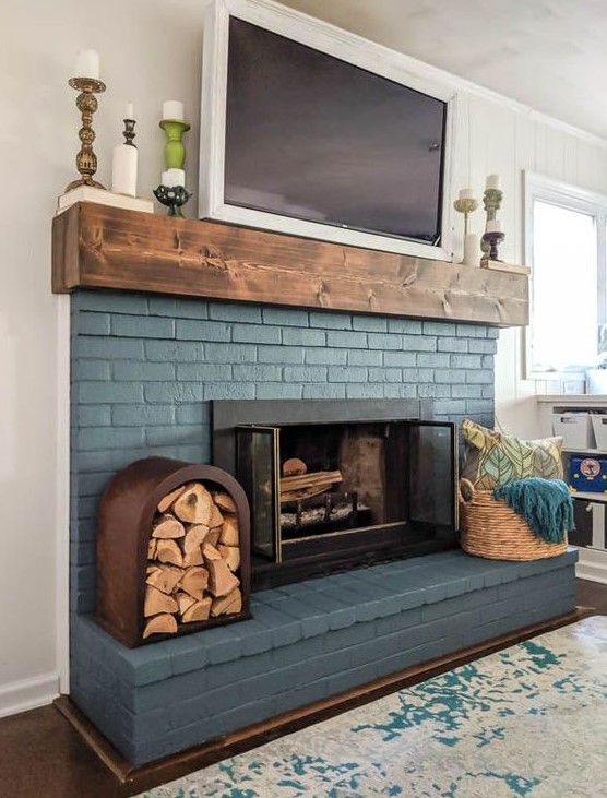a blue brick fireplace is lovely finished off with a wooden mantel and accented with a basket with towels and a firewood storage