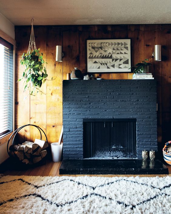 a boho living room with a graphite grey brick fireplace, some decor, potted plants and firewood in a stand is a chic space