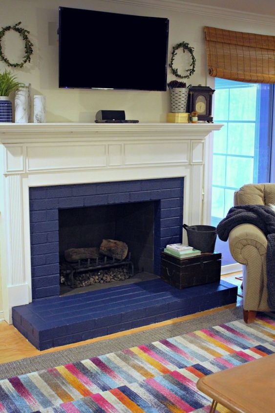 a colorful space with a navy brick fireplace and a white mantel, a colorful rug and some mantel decor